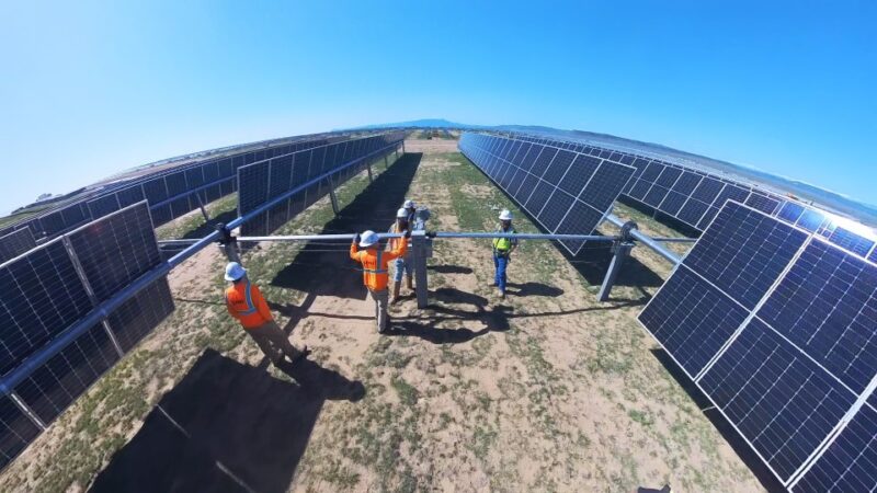 Weitwinkelaufnahme zeigt Bau an einem Freiflächensolarpark in trockener Landschaft.