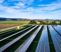 Freiflächensolarpark in flacher Landschaft unter blauem Himmel.