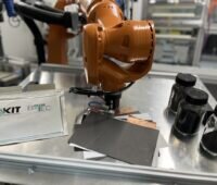 Bild zeigt einen Roboterarm, einige Folien und schwarzes Granulat in Gläsern - Batterie-Recycling am KIT.