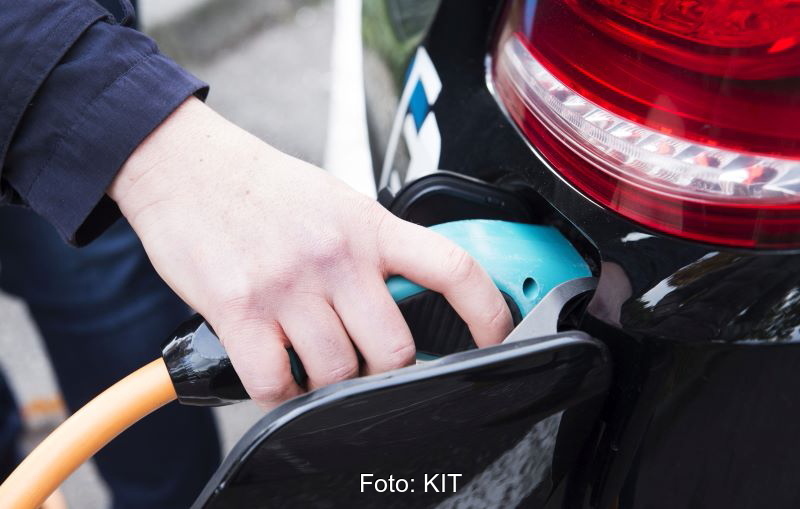 Eine Hand am Stecker beim Laden des E-Autos.