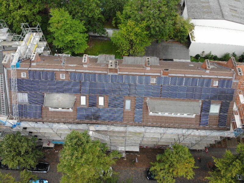 Ein Wohnblock mit PV auf dem Dach aus der Vogelperspektive