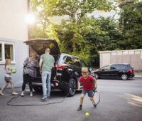 Eine Familie packt ihr Elektroauto, das gerade geladen wird.