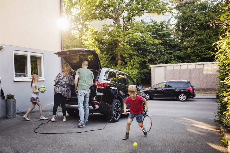 Eine Familie packt ihr Elektroauto, das gerade geladen wird.