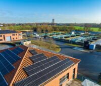 Luftbild einer Kläranlage mit Wasserbecken und PV auf den Gebäuden.