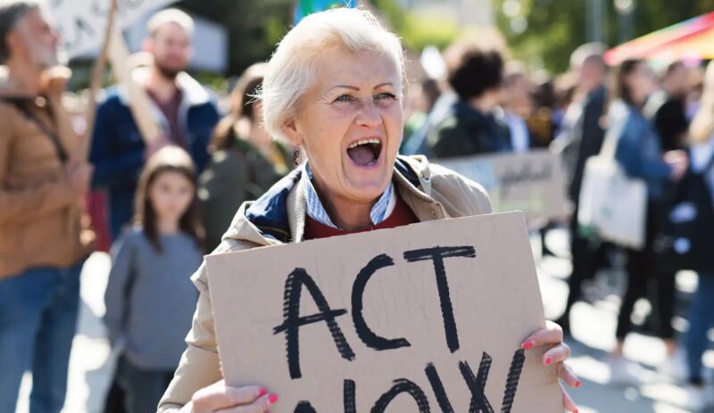 Frau mit Pappschild "Act now" - Symbol für Klimaklage von BUND und SFV.