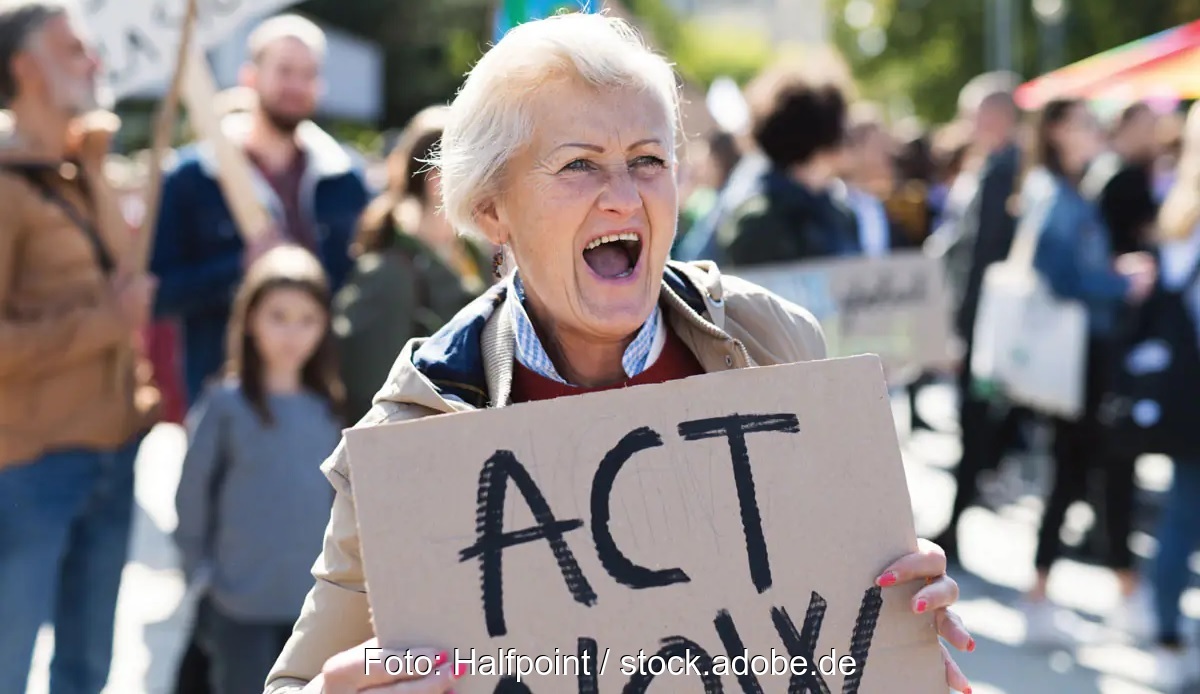 Frau mit Pappschild "Act now" - Symbol für Klimaklage von BUND und SFV.
