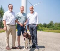 Im Bild Firmenvertreter von KB Renewables und Koehler vor Windenergie-Anlagen.