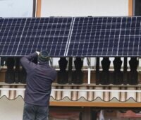 Zu sehen ist ein Mann, der ein Balkonkraftwerk installiert, dafür gibt nun Geld im Solarförderprogramm der Stadt Essen.