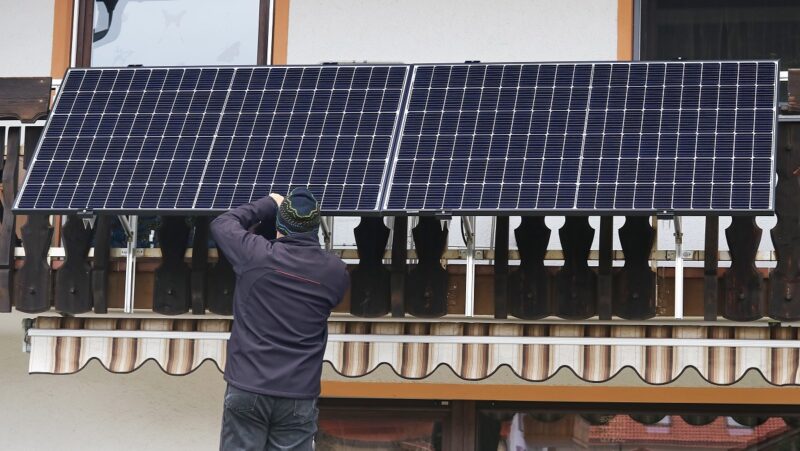 Zu sehen ist ein Mann, der ein Balkonkraftwerk installiert, dafür gibt nun Geld im Solarförderprogramm der Stadt Essen.