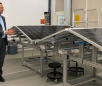 Ein Manager im Anzug vor zusammenklappbaren Solarmodulen.