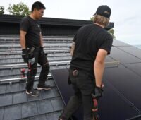 Zwei Installateure bei der Montage von Solarmodulen auf einem Schrägdach.