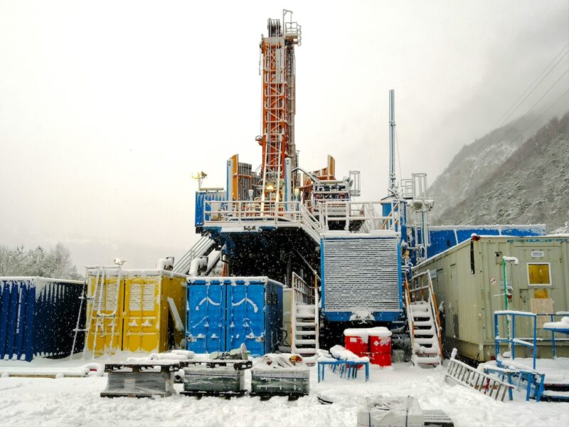 großer Geothermie-Bohrturm in verschneiter Landschaft.