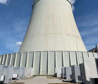 Eine Reihe von Batteriespeichern vor einem Kühlturm eines Braunkohlekraftwerks