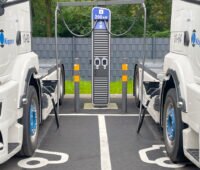 Zwei Elektro-Sattelschlepper-Trucks an einer Ladesäule.