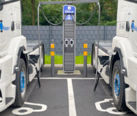 Zwei Elektro-Sattelschlepper-Trucks an einer Ladesäule.