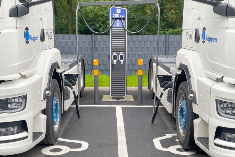 Zwei Elektro-Sattelschlepper-Trucks an einer Ladesäule.
