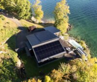 Blick von oben auf eine Hütte am Wasser mit PV-Anlage mit Longi Hi-Mo 6 Modulen