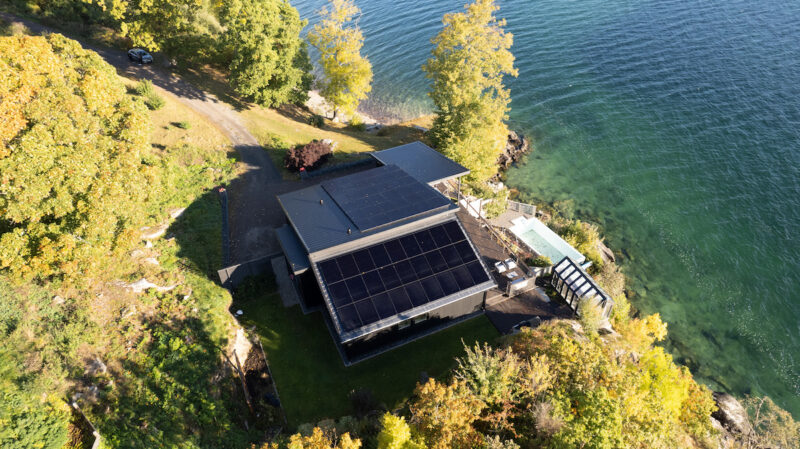 Blick von oben auf eine Hütte am Wasser mit PV-Anlage mit Longi Hi-Mo 6 Modulen