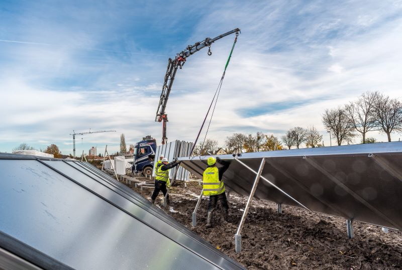 Arbeiter in gelben Westen installieren Solarkollektoren.