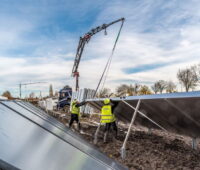 Arbeiter in gelben Westen installieren Solarkollektoren.