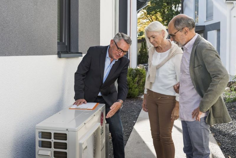 Mann im Anzug, älteres Paar und Wärmepumpe.