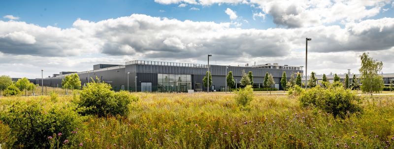 Ein modernes Industriegebäude umgeben von bunten Blumen und Büschen.