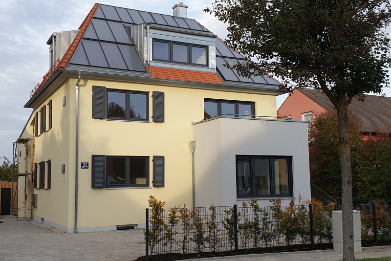 Ein Mehrfamilienhaus mit einer Solarthermieanlage auf dem Spitzdach.