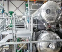 Silber-glänzende Rohrleitungen und technische Anlagen der ersten MVV-Flusswärmepumpe in Mannheim.