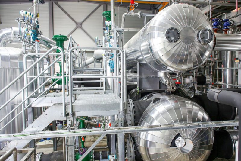 Silber-glänzende Rohrleitungen und technische Anlagen der ersten MVV-Flusswärmepumpe in Mannheim.
