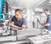 Arbeiter bedienen moderne Maschinen für elektrotechnische Anwendungen