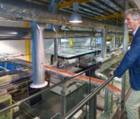 Mann schaut von Empore auf Fabrikhalle - Green in Photovoltaik-Fabrik als Symbol für Bedeutung der PERC-Solarzelle
