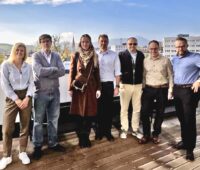 Die Verantwortlichen stehen gemeinsam auf dem Dach eines Hochhauses mit Stadt und blauem Himmel im Hintergrund und freuen sich über die BESS-Partnerschaft zwischen MaxSolar und Greenvolt Power.