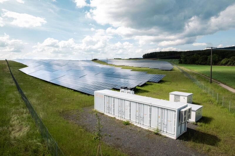 KI generierte Simulation zeigt PV-Freiflächenanlage mit einem Batteriespeicher.