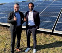 Zwei Männer stehen vor Photovoltaik-Anlage und halten den Daumen hoch - Maxsolar übernimmt Projektpipeline