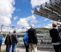 Ein Helioflex-Solarfaltdach über einem Klärbecken in der Schweiz fährt gerade zusammen in den eingeklappten Modus.