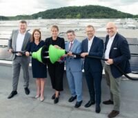 Im Bild Offizielle mit grünem Riesenstecker bei der Einweihung für die größte Photovoltaik-Dachanlage Deutschlands.