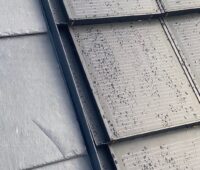 Detailaufnahme: Graues Schiefer-Dach, Solarziegel in grau, mit Regentropfen