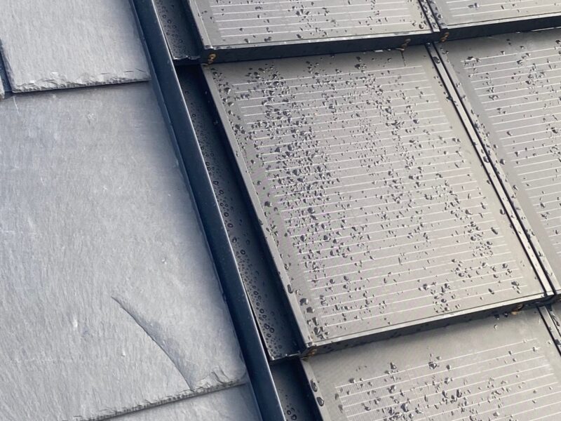 Detailaufnahme: Graues Schiefer-Dach, Solarziegel in grau, mit Regentropfen