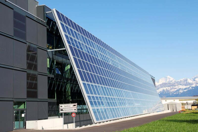 Zu sehen ist eine Solarfassade der Firmenzentrale von Meyer Burger, im HIntergrund die Alpen.