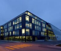 Ein Bür0gebäude in der Dämmerung mit neleuchteten Fenstern.