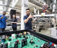 Fertigung von Photovoltaik-Wechselrichtern bei SMA in Kassel. Die Hauptplatine von einem Wechselrichter mit zahlreichen elektronischen Bauteilen ist offen sichtbar.