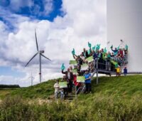 Menschen vor Windenergieanlage, der Michael-Sladek-Preis für Bürgerenergie wird erstmals ausgelobt.