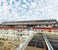 Blick über Solardach auf weiteres Gebäude mit Solardach und Baugerüst - Mieterstrom-Projekt von Enerfin.