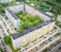 Karree aus vier Gebäudeblöcken in verschiedenen Farben, auf dem Dach Photovoltaik-Module - Mieterstrom-Projekt in Berlin.