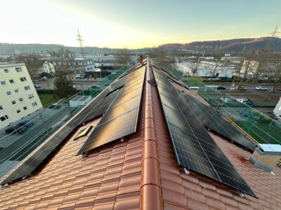 Solarmodule auf einem Mehrfamilienhaus mit Satteldach im urbanen Umfeld.