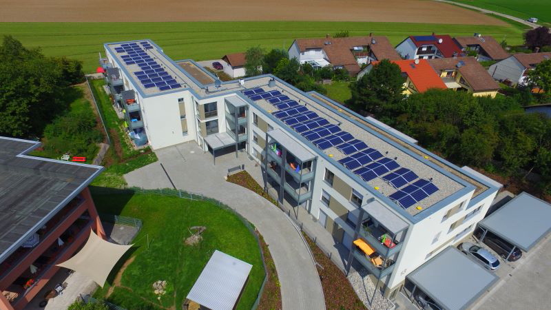 Luftbild einer Mehrfamiliensiedlung mit Photovoltaik auf den Dächern.