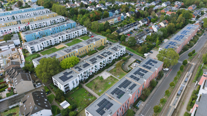 Luftaufnahme der Ossendorfer Gartenhöfe in Köln: Auf den Dächern mehrerer Wohngebäude sind Photovoltaikmodule zu sehen. Zwischen den Häusern liegen begrünte Innenhöfe.