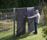 Im Bild ein Mann, der die Zaun-Solaranlage von Greenakku installiert.