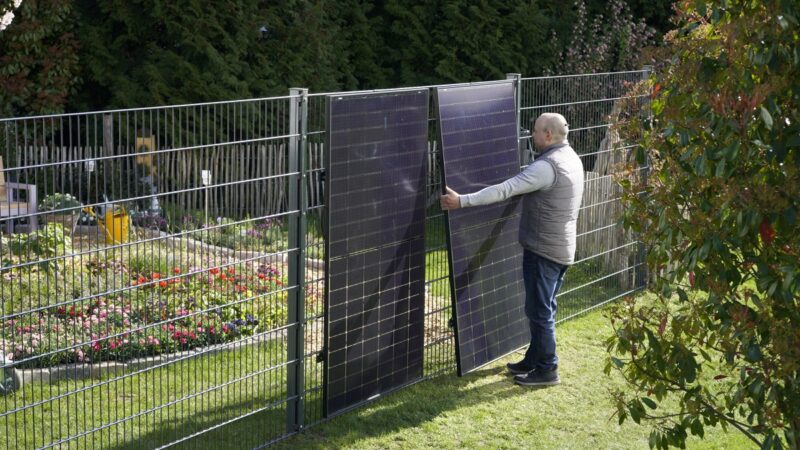 Im Bild ein Mann, der die Zaun-Solaranlage von Greenakku installiert.