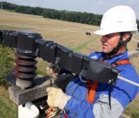 Im Bild ein Arbeiter auf einem Spannungsmast der Mitnetz Strom, für den Natzbetrieber steht die Digitalisierung der Mittel- und Niederspannungsnetze im Fokus.